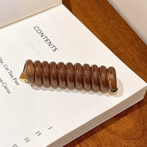 Détail d'élastique spirale ambre avec fermoir doré sur fond de livre vintage