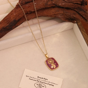 Detail view of a vintage gold necklace with purple enamel pendant on a display stand