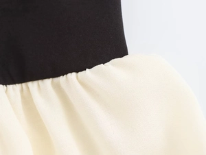 Detail view of the stitching and fabric texture on a black and cream patchwork dress