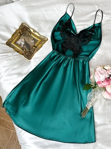 Détail de la chemise de nuit en satin vert foncé avec dentelle papillon noire délicate