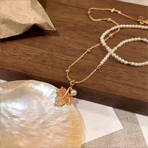 Détail du collier feuille d'érable avec perles sur fond de coquillage et bois