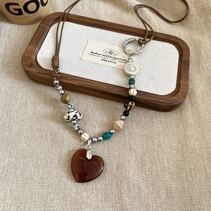 Detail of bohemian beaded necklace with amber heart pendant on wooden tray