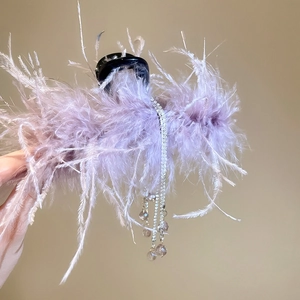 Detail of purple feather hair claw clip with rhinestones tassels and crystal charms
