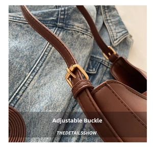 Detail of adjustable gold buckle on brown matte leather shoulder strap over denim