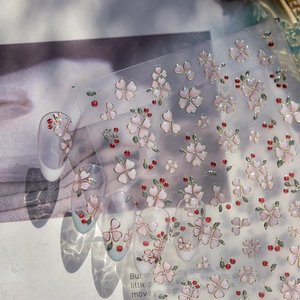 Detail of jelly nail stickers featuring pink flowers, red cherries and golden outlines