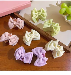 Macro shot of assorted macaron-colored satin bow hair claws on a wooden tray