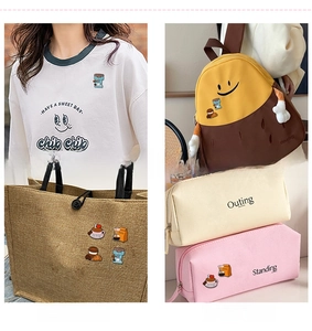Macro detail of coffee-themed enamel pins on various fabric surfaces like bags and clothing