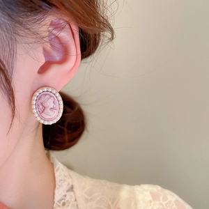 Close-up of pink portrait cameo earrings with pearl border and French vintage aesthetic