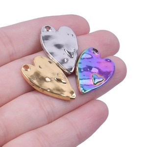 Detailed view of heart-shaped stainless steel pendants with embossed texture on hand