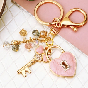 Detail of a gold-plated keychain with pink heart charm, crystal key and colorful beads