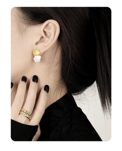 Close-up of dual-tone geometric earrings and ring set with irregular ore texture