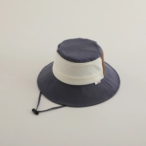 Detail of color-block kids bucket hat with adjustable chin strap and fabric brand label