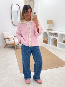 Pink chunky knit cardigan paired with blue heart pattern denim wide-leg jeans in a mirror selfie