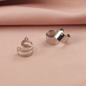 Minimalist silver stainless steel ear cuffs and jewelry findings on pink fabric