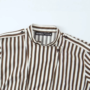 Détail d'une chemise à rayures verticales marron et bleu marine avec col et étiquette de marque