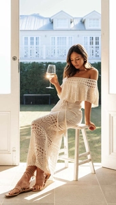Dettaglio dell'abito lungo in maglia all'uncinetto bianco crema con scollatura a barchetta