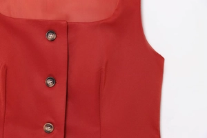 Detailed macro view of the red sleeveless top showing textured fabric and brown buttons