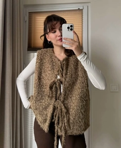 Detail view of the brown fuzzy mohair vest with front tie closure worn over white long sleeve