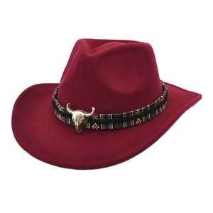 Detalle de sombrero vaquero rojo oscuro con banda étnica y adorno de calavera de toro dorada