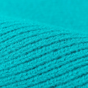 Macro close-up shot of vibrant turquoise knitted fabric texture for winter beanies