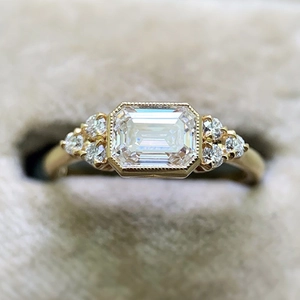 Vista macro de anillo con diamante de talla esmeralda y detalles milgrain en terciopelo