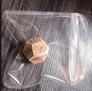Detail of wooden date night dice with engraved activity icons in clear packaging