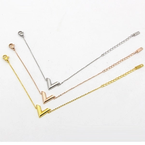 Detailed view of V-shaped letter charms on gold, rose gold and silver thin link bracelets