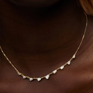 Close-up of elegant gold necklace featuring nine pear-cut zircons on a female model