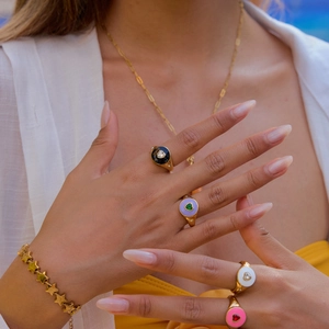 Close-up of gold stainless steel heart rings with colorful enamel and star chain bracelet