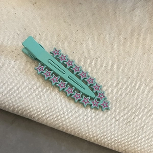 Barrette à cheveux turquoise à motif étoilé sur fond de lin beige avec vue à 45 degrés