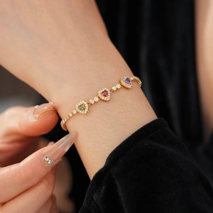 Close-up of 18k gold heart bracelet with colorful zircons worn on a wrist