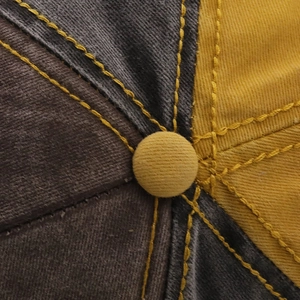 Macro shot of tricolor baseball cap top with yellow contrast stitching and button detail