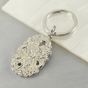 Detailed close-up of a silver dragon pendant with intricate carvings and metal keyring