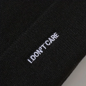 Black ribbed knit beanie with white I DON'T CARE embroidery in minimalist street style