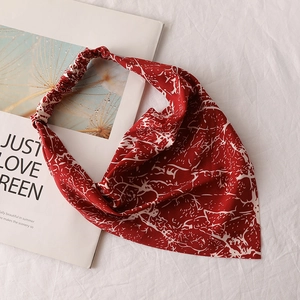 Detail view of burgundy floral chiffon head scarf with elastic band on an art book