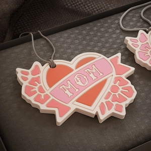 Dettaglio del ciondolo MOM a cuore con rilievo rosa multistrato e cordino per appenderlo