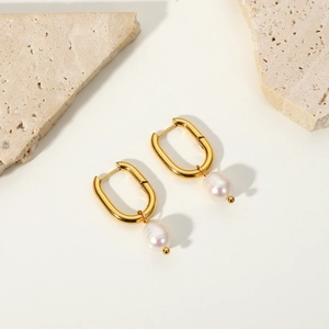 Elegant gold U-shaped hoop earrings with white drop pearls on a minimalist stone base