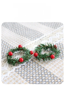 Detailed view of two Christmas pine needle napkin rings with red berries and lush greenery