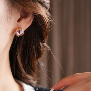 Close-up of a pink crystal earring with a gold base and micro-inlaid zircon details