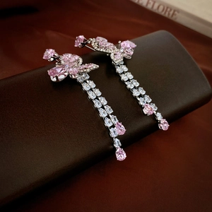 Detailed macro view of silver needle drop earrings with pink zircon butterfly tassel charms