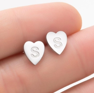 Gros plan macro d'une boucle d'oreille cœur en acier inoxydable avec gravure lettre S