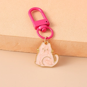 Close-up of a cute pink cat keychain with gold metal edges and matching pink clasp