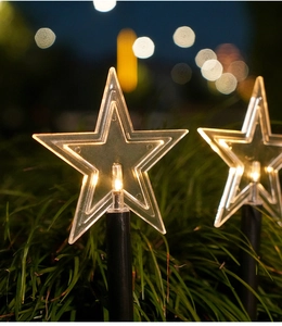 Close-up of star-shaped solar garden lights with warm LED glow in the night grass