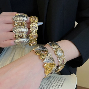 Detail of vintage heart charms and engraved silver-gold bracelets on a model's wrist