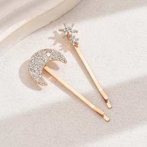 Sparkling gold alloy moon and stars hair clip set with rhinestones on a textured background