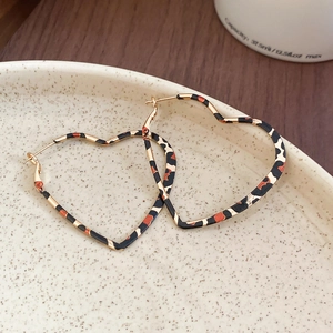 Leopard print heart hoop earrings displayed on a vintage ceramic plate for fashion detail