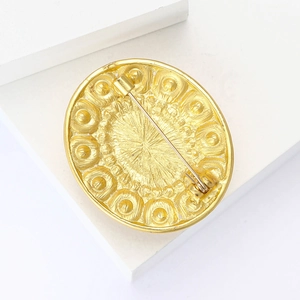 Detail view of the golden vintage brooch back showing the pin clasp and metal texture