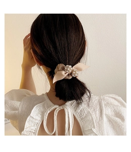 Vue détaillée du nœud en satin champagne avec perles porté sur les cheveux