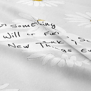Detail of bohemian tapestry fabric showing white daisy print and cursive text texture