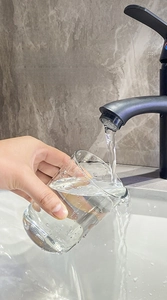 Close-up of a transparent dental cup being rinsed under a faucet for easy cleaning